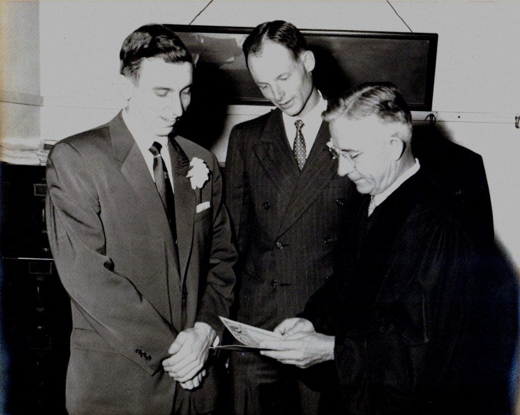 Photo of three men looking at a marriage certificate