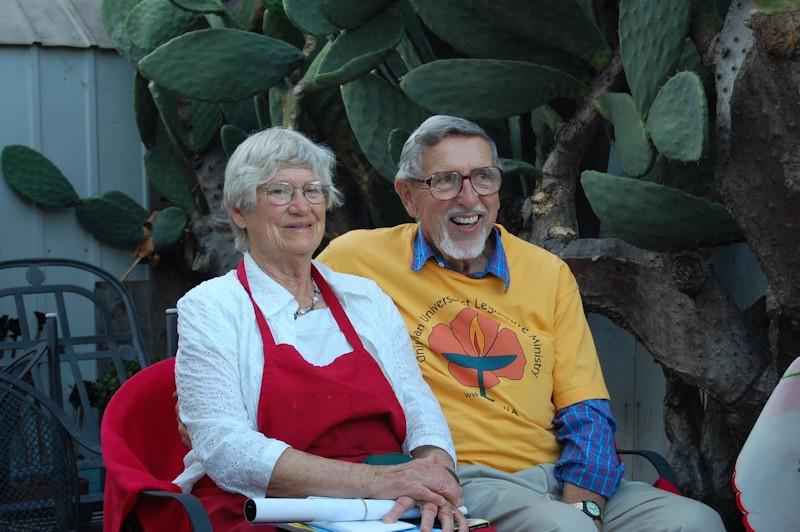 Mary Lee and Bill sitting smiling in front of a large cactus